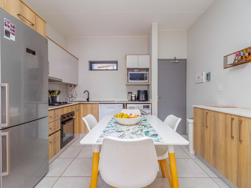 Modern kitchen featuring light wood-tone cabinetry, integrated appliances, gas hob, electric oven, and tiled flooring, offering a functional and contemporary cooking space.
