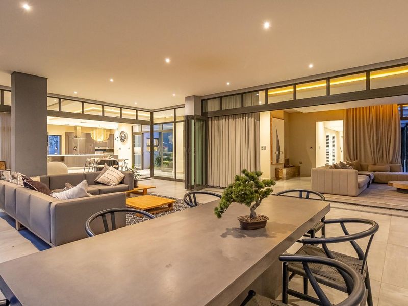 Spacious open-plan living and dining area featuring large format floor tiles, recessed lighting, and expansive aluminium stacking doors leading to outdoor spaces.