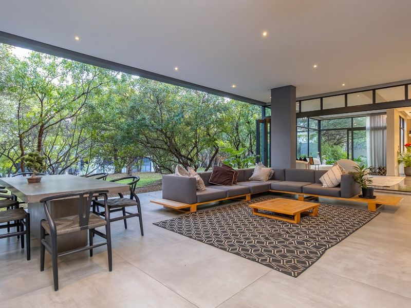 Spacious covered patio featuring large format floor tiles, recessed lighting, and seamless indoor-outdoor flow through bi-fold glass doors overlooking a lush garden.
