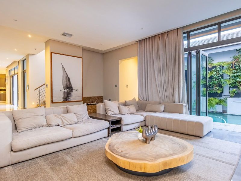 Spacious open-plan living area featuring modern tiled floors, recessed lighting, and seamless indoor-outdoor flow through stacking glass doors to the pool area.