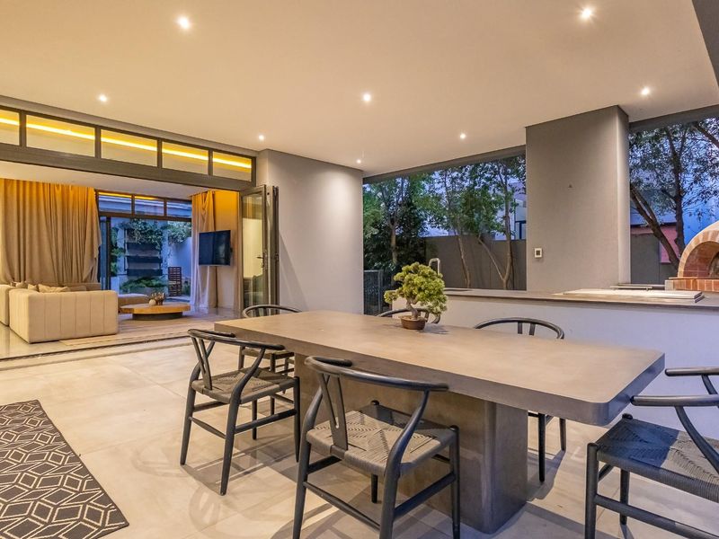 A spacious covered patio featuring a built-in pizza oven, tiled flooring, and seamless access to the interior living area through stacking glass doors.