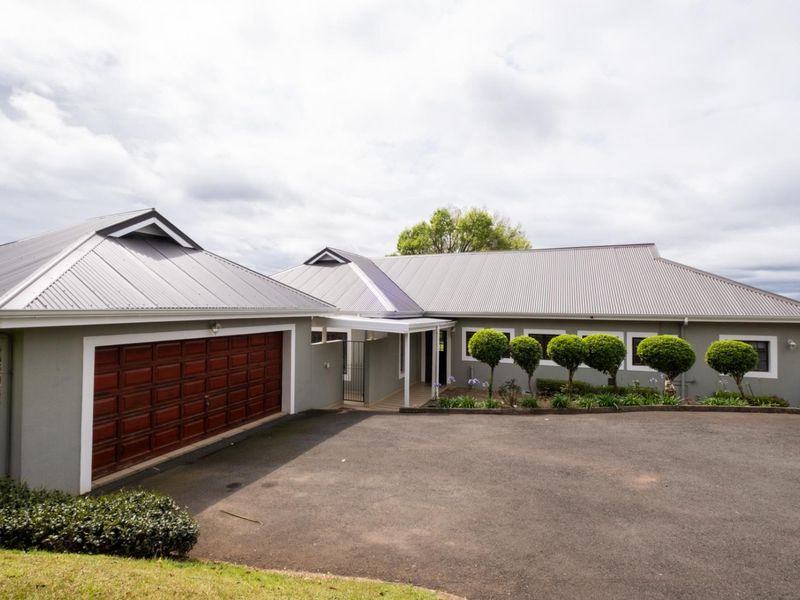 Front elevation of a townhouse featuring a metal roof, double garage, and paved driveway with a covered entrance walkway.