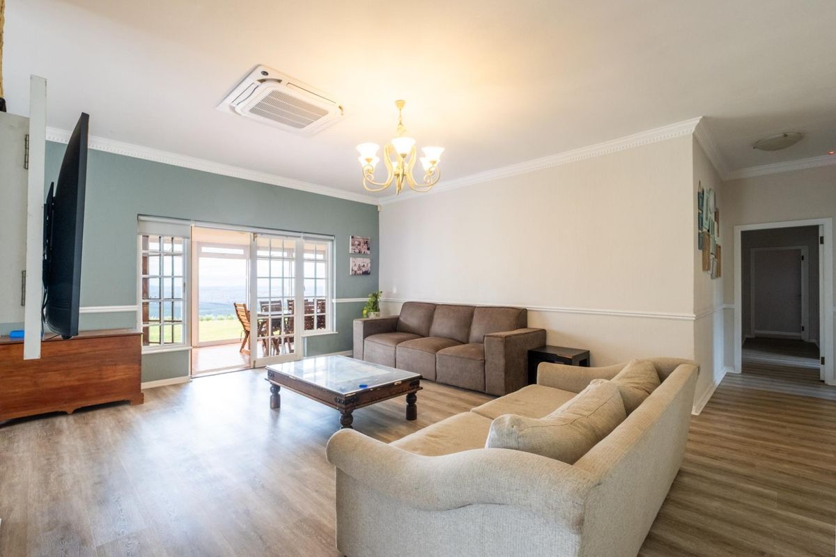 Spacious living room featuring laminate flooring, crown molding, chair rail, and a ceiling-mounted air conditioning unit, with direct access to an outdoor patio area.