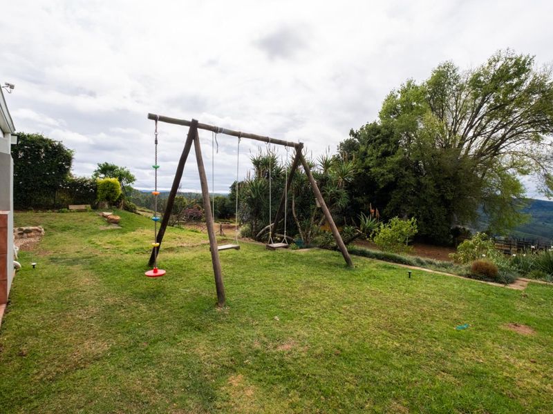 A spacious rear garden featuring a well-maintained lawn, established trees, and scenic views of the surrounding landscape.