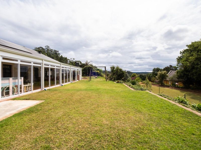Spacious rear garden featuring a well-maintained lawn, retaining wall, and extensive glass sliding doors providing seamless indoor-outdoor flow.