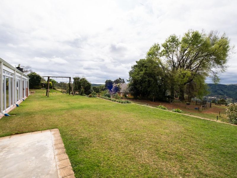 Spacious rear garden featuring a paved patio area, expansive lawn, and sliding glass door access to the townhouse interior.