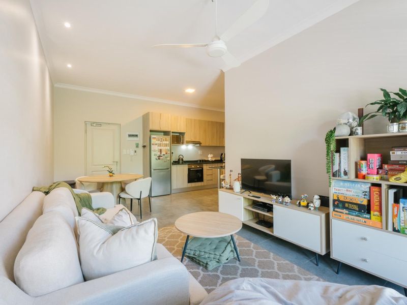 Open-plan living area featuring a modern kitchen with built-in cabinetry, integrated oven, and extractor fan, complemented by tiled flooring and recessed lighting.
