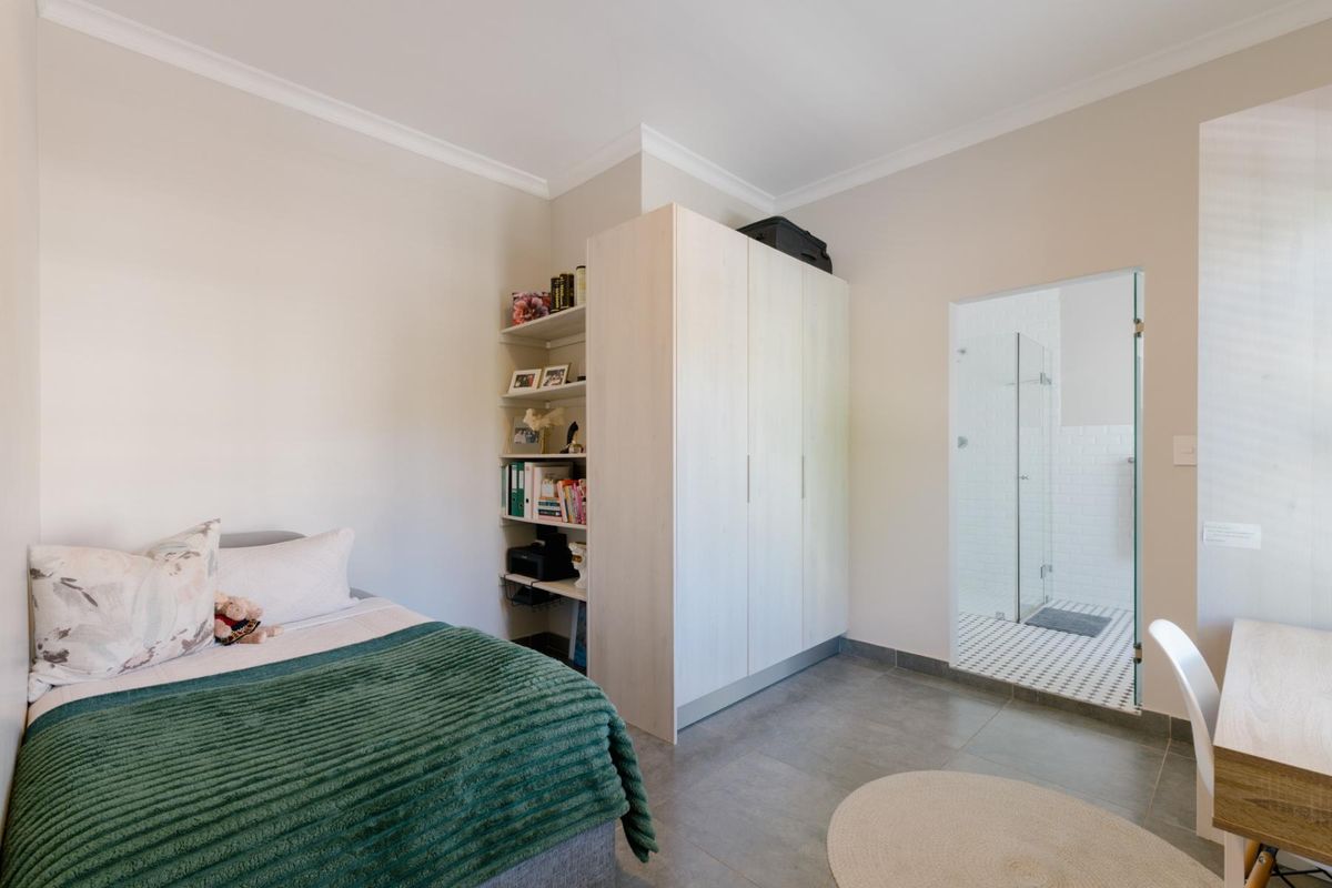 A well-maintained bedroom featuring built-in wardrobes, integrated shelving, tiled flooring, and direct access to an en-suite bathroom.
