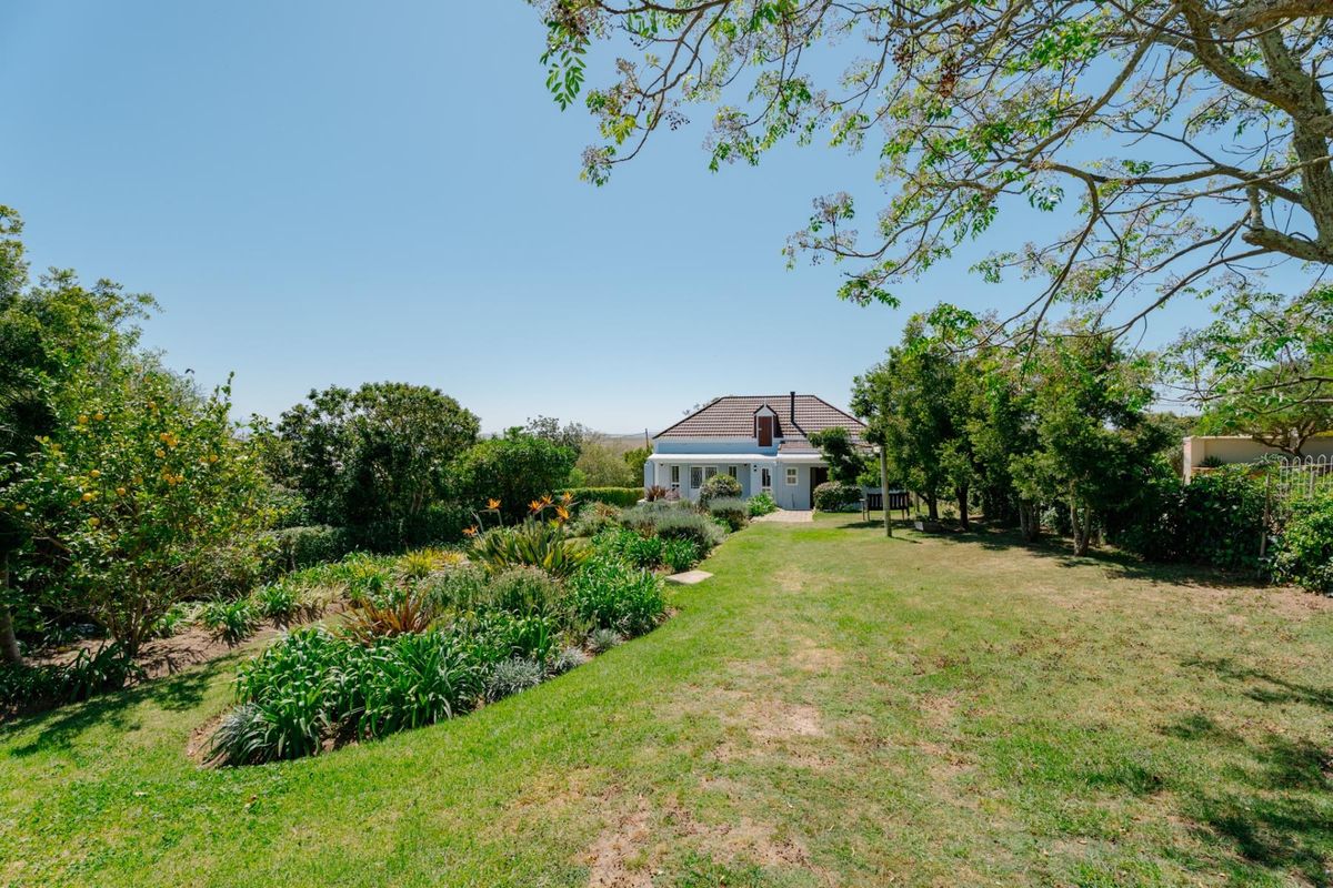 A well-maintained rear garden featuring lush landscaping, mature trees, and a clear view of the property's rear elevation and tiled roof.