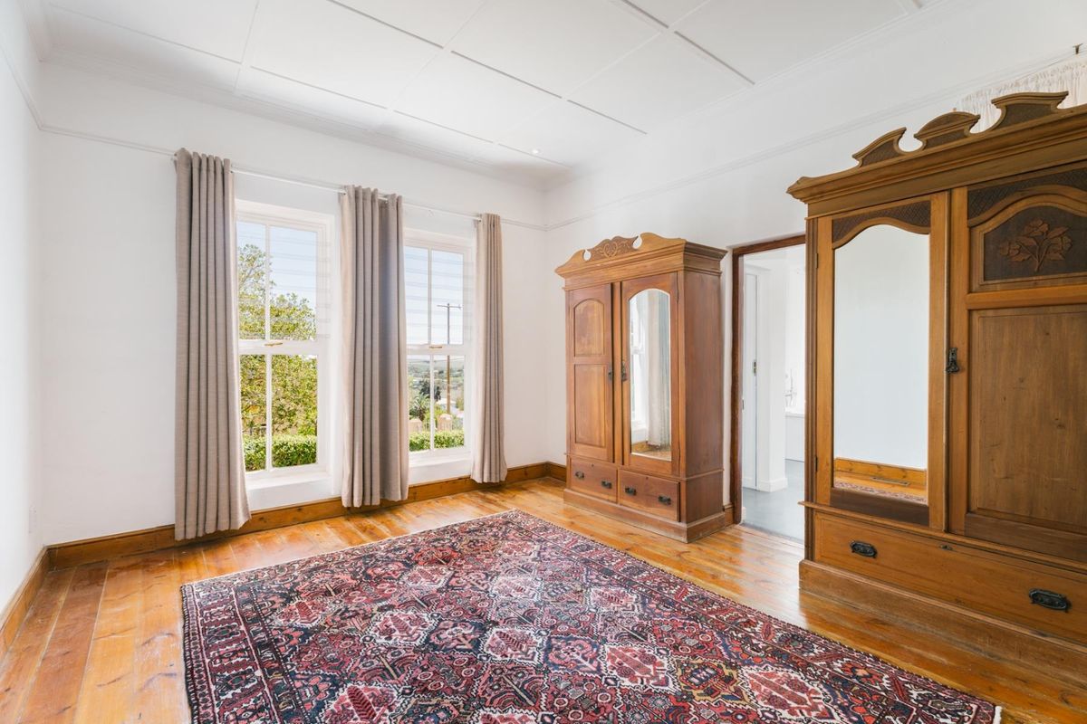 A bright bedroom featuring original timber flooring, classic sash windows, and a high panelled ceiling, offering a warm and character-filled living space.