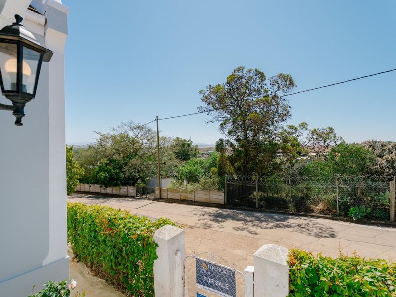 A street-level view showing the property boundary, perimeter fencing with razor wire, and exterior wall lighting.