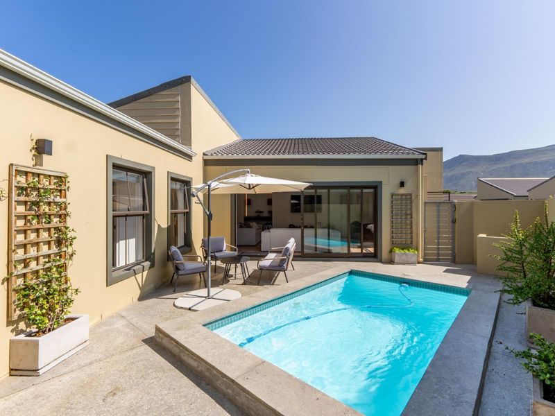 A well-maintained outdoor pool area featuring a paved patio, integrated swimming pool, and direct access to the home through sliding glass doors.