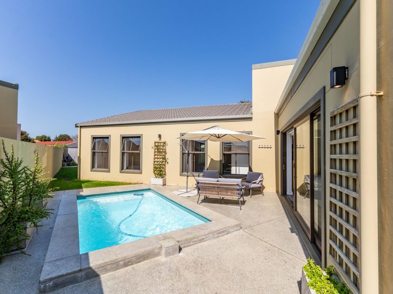 A well-maintained rear courtyard featuring a private swimming pool, concrete patio area, and direct access to the home via sliding glass doors.