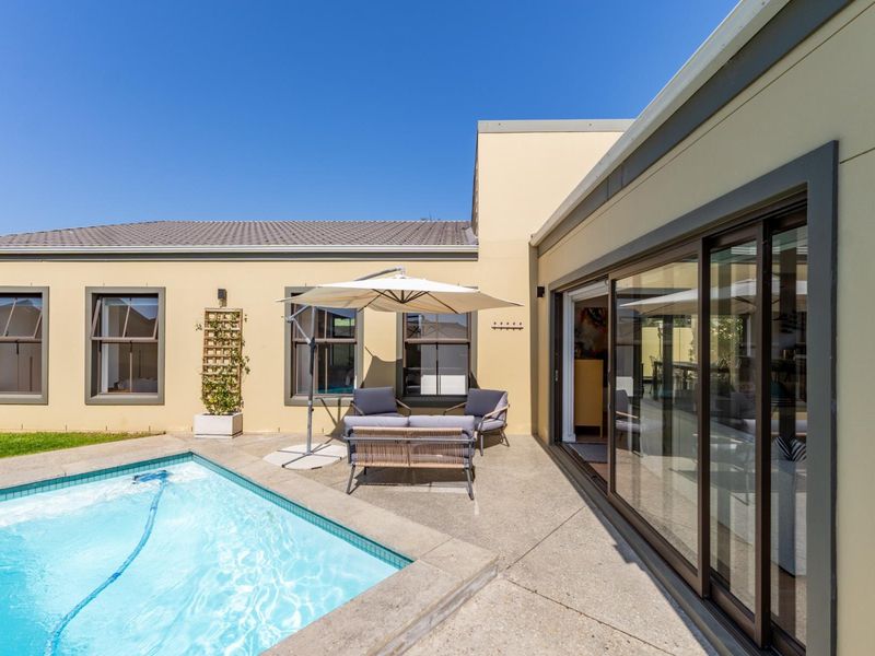A well-maintained outdoor pool area featuring a concrete patio, swimming pool, and large sliding glass doors providing seamless indoor-outdoor flow.