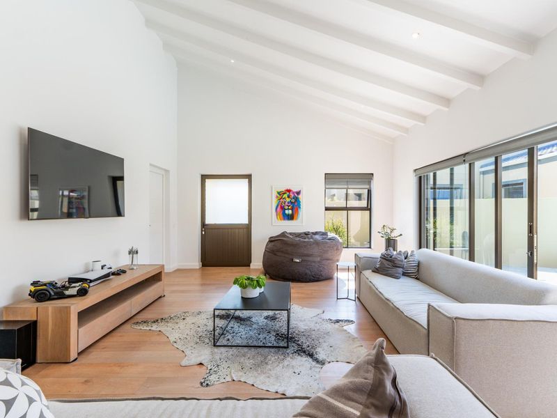 Spacious living room featuring high vaulted ceilings with exposed rafters, timber flooring, and large sliding glass doors providing natural light and pool access.