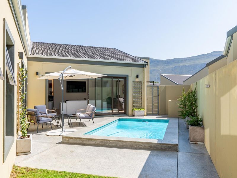 A well-maintained outdoor courtyard featuring a compact plunge pool, concrete patio area, and direct access to the home through sliding glass doors.