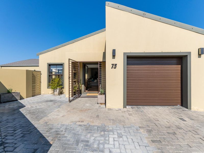 Front elevation of a modern house featuring a paved driveway, single garage with a brown sectional door, and a secure entrance.
