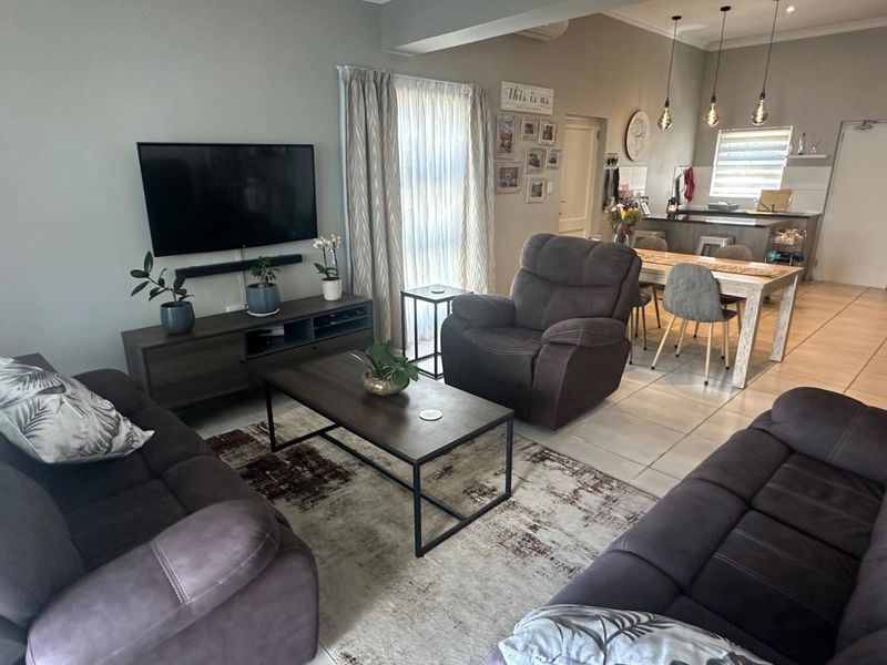 An open-plan living and dining area featuring tiled flooring, modern pendant lighting, and a functional kitchen with a central island.