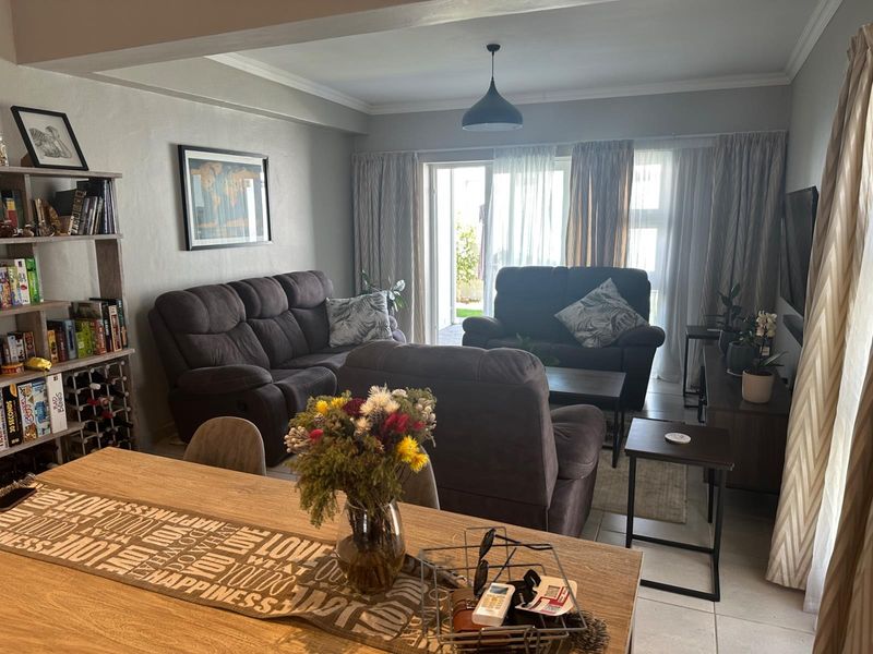 Open-plan living area featuring tiled flooring, coving, and a sliding glass door providing access to the outdoor space.
