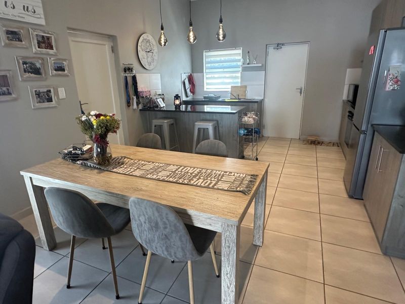 Open-plan kitchen and dining area featuring tiled flooring, modern cabinetry, granite countertops, and pendant lighting, creating a functional and cohesive living space.