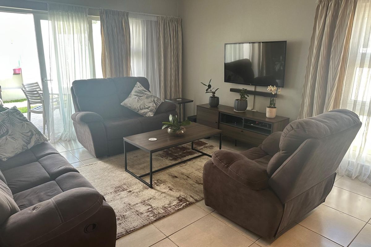 A comfortable living room featuring tiled flooring and large sliding glass doors that provide access to the outdoor patio area.