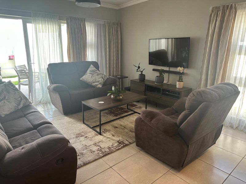 A comfortable living room featuring tiled flooring and large sliding glass doors that provide access to the outdoor patio area.