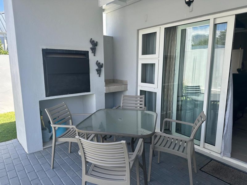 A covered patio area featuring a built-in braai and sliding glass door access to the interior living space.
