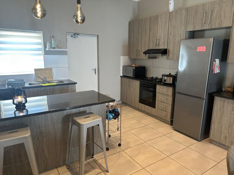 Modern kitchen featuring wood-grain cabinetry, granite countertops, built-in oven with gas hob, extractor fan, and tiled flooring.