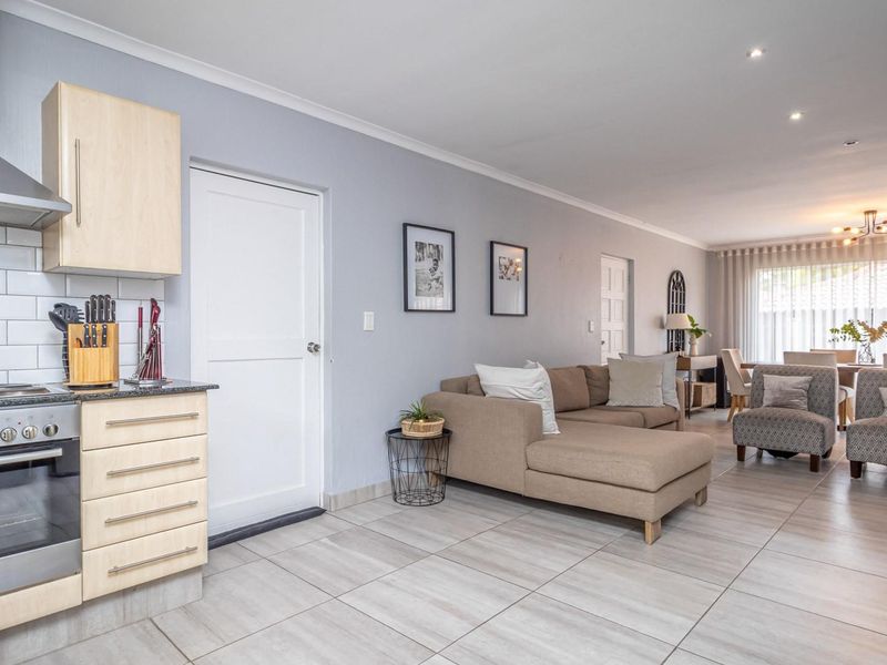 Spacious open-plan living area featuring a modern kitchen with stainless steel appliances, tiled flooring, and seamless flow into the dining and lounge spaces.