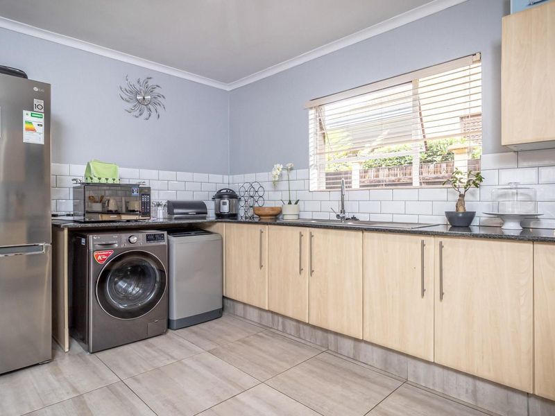 A functional kitchen featuring light wood cabinetry, granite countertops, a subway tile backsplash, and neutral ceramic floor tiles.