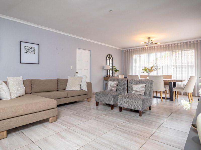 Spacious open-plan living and dining area featuring neutral tiled flooring and ample natural light through large windows.