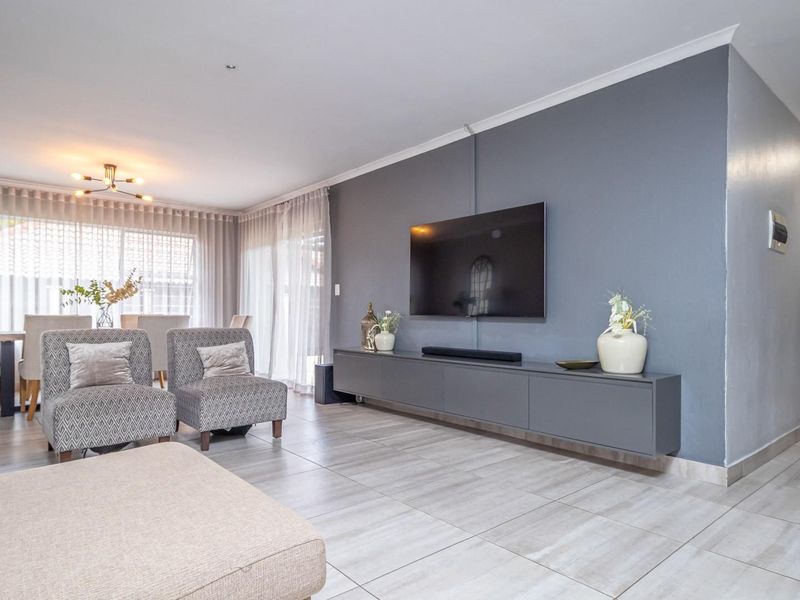 Spacious open-plan living and dining area featuring modern tiled flooring, a sleek floating media console, and large sliding doors providing ample natural light.