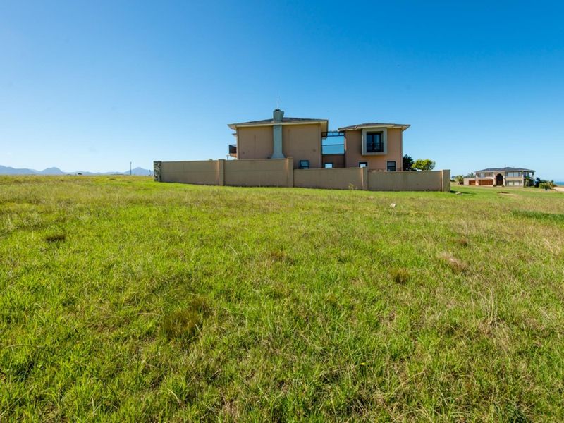 A view of a vacant residential plot featuring a boundary wall and a neighboring house in the background.