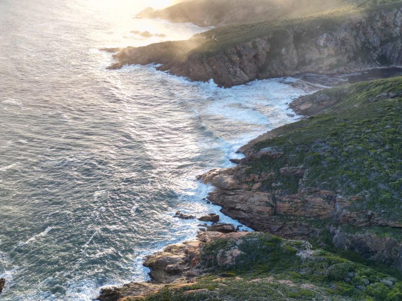 An aerial view of the rugged coastal landscape, showcasing the rocky shoreline and ocean waves.
