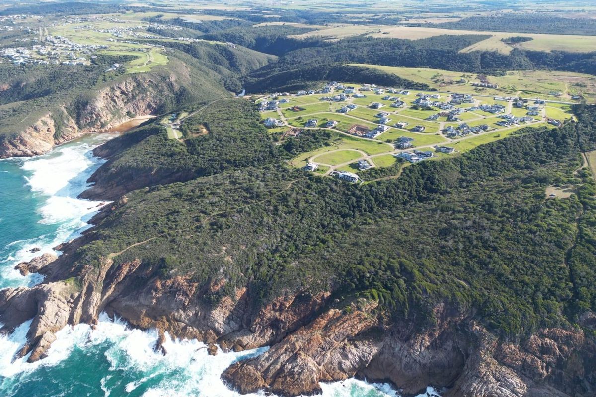 An aerial view of a coastal residential estate situated on a cliffside, showcasing the surrounding landscape and ocean proximity.
