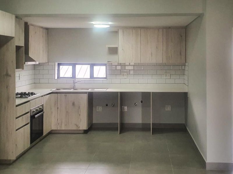 Modern kitchen featuring light wood-look cabinetry, subway tile backsplash, integrated oven, gas hob, and dedicated under-counter space for appliances.