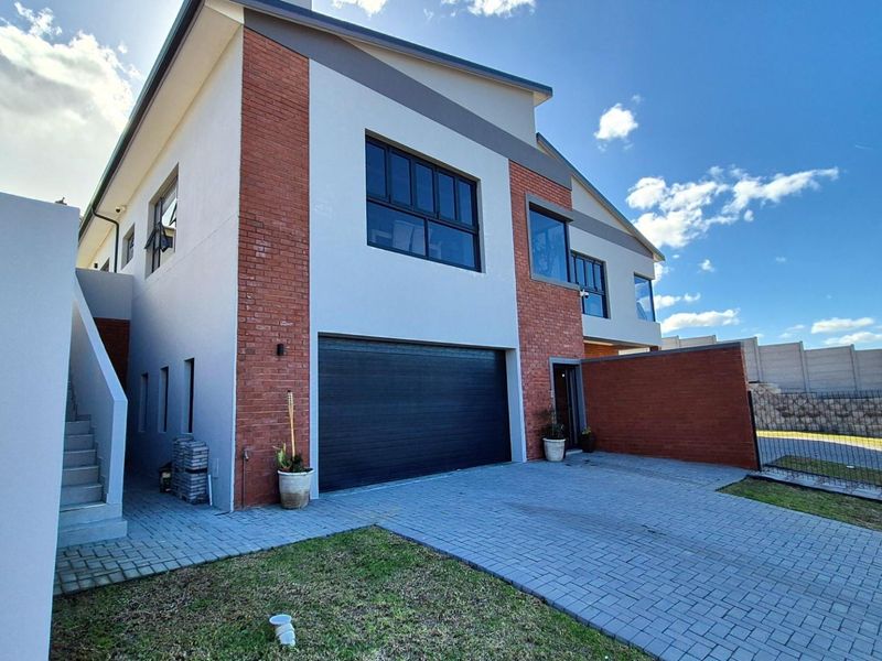 Modern double-storey duet property featuring a brick and plaster facade, paved driveway, and a secure double garage.