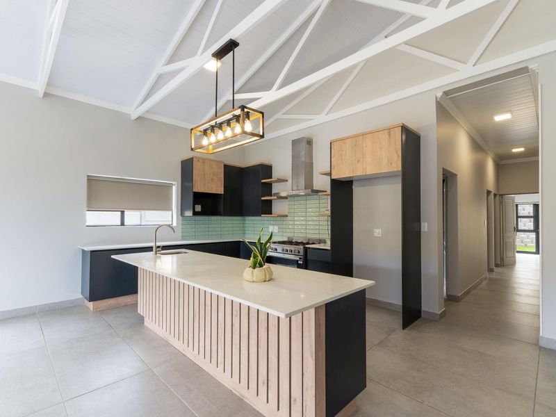 Modern kitchen featuring a central island with stone countertops, built-in cabinetry, tiled backsplash, and high vaulted ceilings with exposed white trusses.