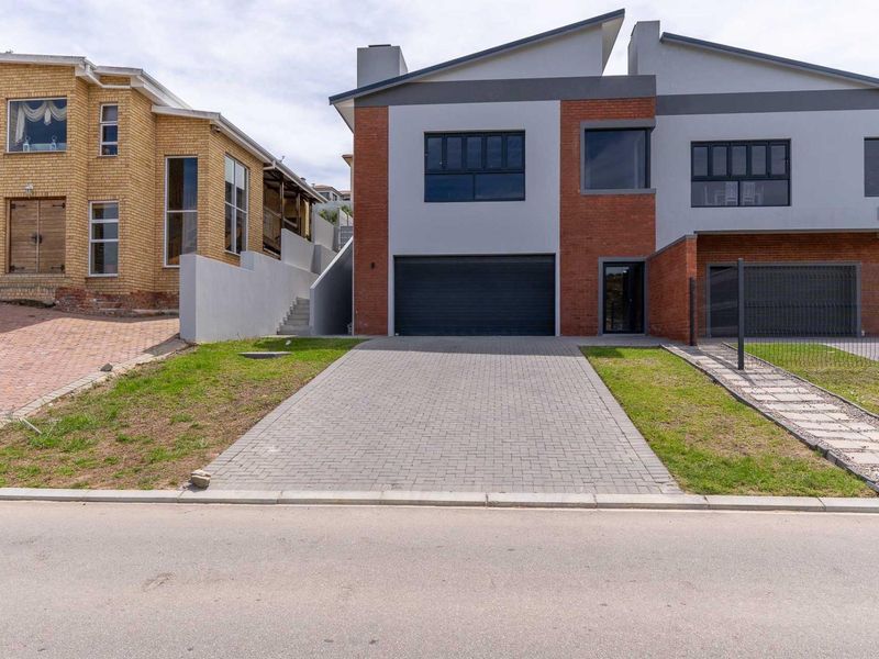 Front elevation of a modern duet property featuring a paved driveway, double garage, and a combination of brick and plastered exterior finishes.