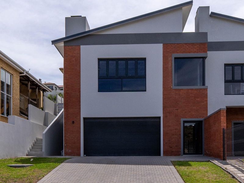 Modern duet property featuring a double garage, paved driveway, and contemporary brick and plaster facade with an external staircase.