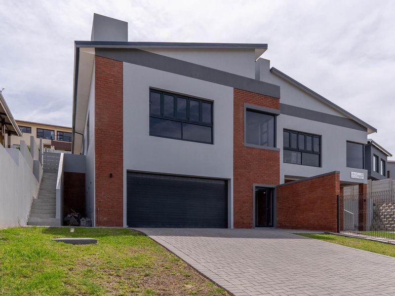 Modern duet property featuring a brick and plaster facade, paved driveway, double garage, and external staircase access.