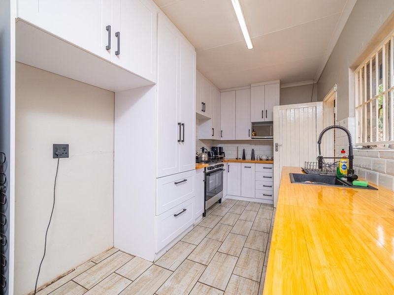 A modern kitchen featuring white cabinetry, wooden countertops, a gas stove, and a subway tile backsplash with a functional layout.