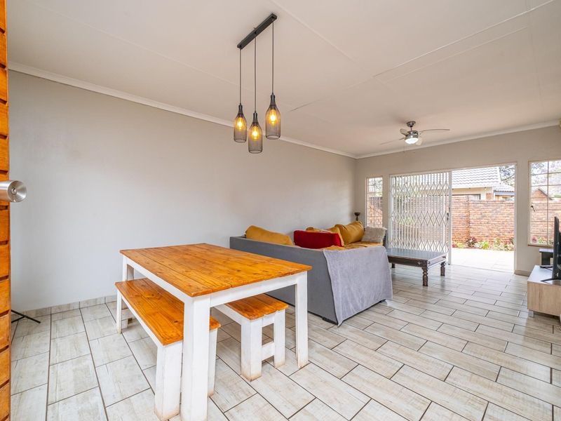 Open-plan living and dining area featuring tiled flooring, modern pendant lighting, and a sliding glass door providing access to the rear patio.