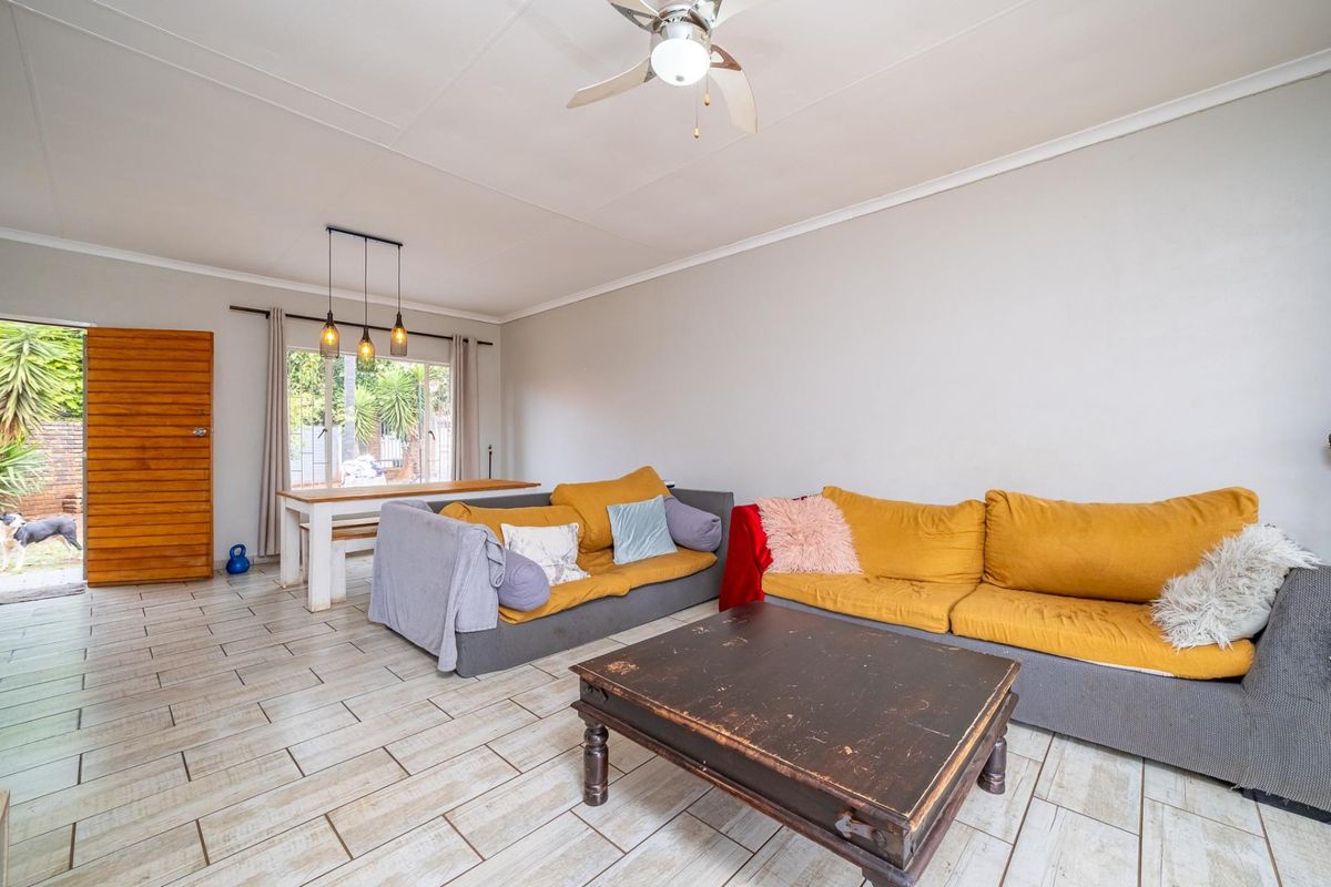 A bright living area featuring tiled flooring, a ceiling fan, and direct access to the outdoor space through a sliding glass door.