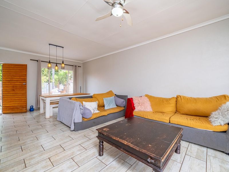 A bright living area featuring tiled flooring, a ceiling fan, and direct access to the outdoor space through a sliding glass door.