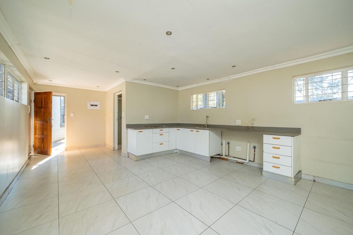 An open-plan kitchen area featuring tiled flooring, built-in cabinetry, and a sink, offering a blank canvas for customization.