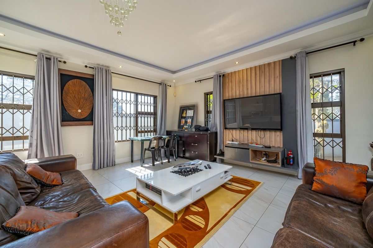 A well-maintained living room featuring tiled floors, recessed ceiling lighting, and a modern timber slat feature wall with integrated media storage.