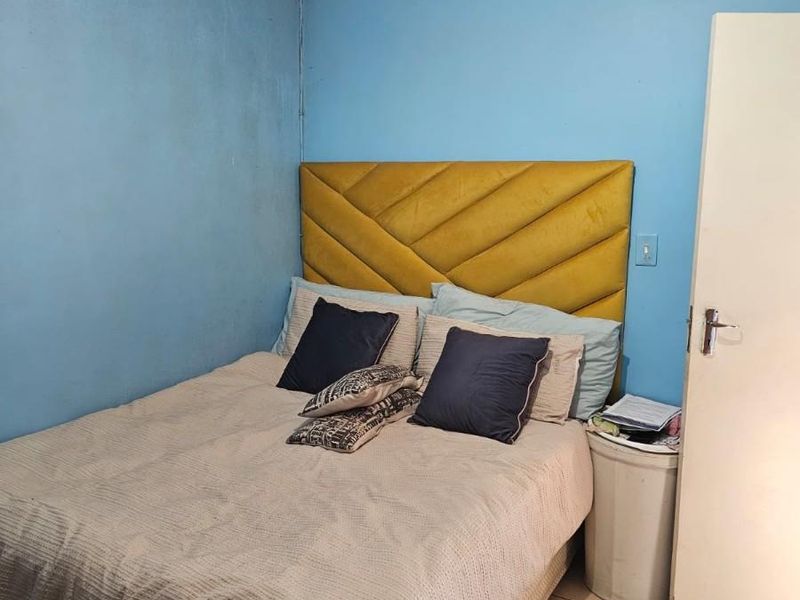 A bedroom featuring tiled flooring and blue painted walls, currently showing signs of ceiling water damage and general wear.