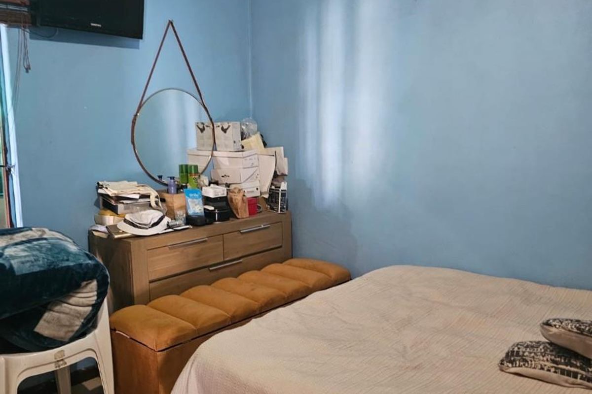 A bedroom featuring tiled flooring and blue painted walls, currently requiring ceiling maintenance and cosmetic updates.