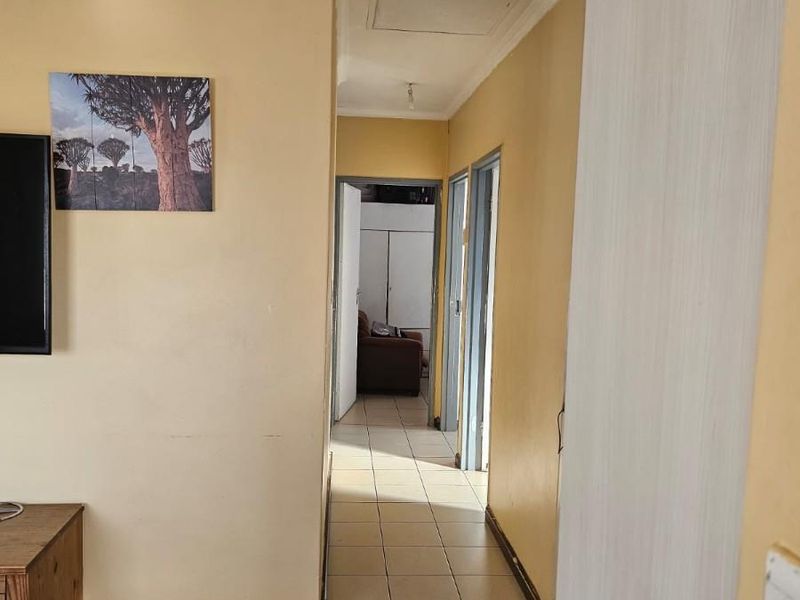A functional hallway featuring tiled flooring and a ceiling access hatch, connecting various rooms within the home.